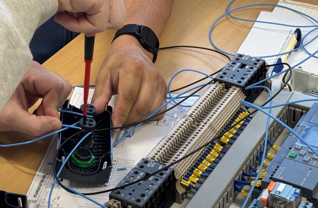 Närbild på två händer som skruvar i en eldosa.